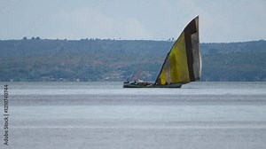 A traditional dhow sails through the estuary near Inhambane, Mozambique, transporting people to the Barra Peninsula, reflecting local maritime culture.