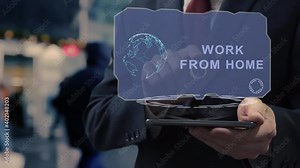Unrecognizable businessman uses hologram on smartphone with text Work From Home. Man in shirt and jacket with holographic screen on background of entrance to the airport or train station