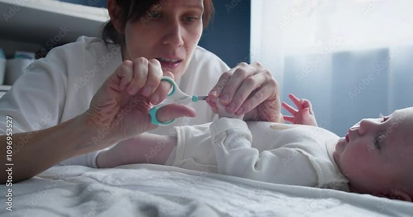 Cutting baby infant newborn nails, mother hands using nail clipper to trim baby finger nails