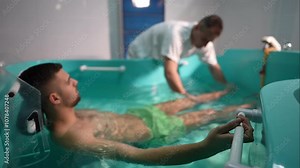 Close-up of a therapist performing hydrotherapy for leg and knee rehabilitation in a spa setting, gently supporting the patient's foot underwater. Concept of physical therapy and healing