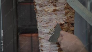 Street food restaurant, making shawarma. The chef cuts meat to cook shawarma. Cooking meat on a skewer for kebab or shawarma.