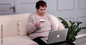 Mature woman making online shopping using laptop and credit card at home.