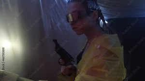 Cyberpunk future. Female bionic cyborg girl with revolver pistol gun walks down corridor with plastic film wrap, lighting blinks, flashes of light. Science fiction scene. Secret scientific laboratory