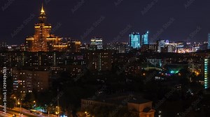 Timelapse architecture night city on dark sky landscape. Night illumination in modern city. Moon moving in cloudy sky over dark city. Night city landscape from drone