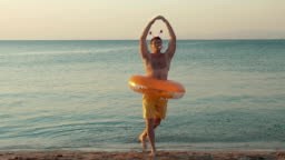 Young funny man with rubber ring performing humorous ballet dancing...
