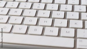 Slow pan along keys on white computer keyboard, close-up