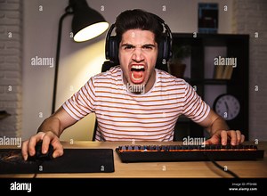 Portrait of angry irritated gamer guy screaming while playing video games on computer wearing headphones and using backlit colorful keyboard Stock Photo - Alamy