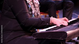 Musical concert. Close-up of female hands playing a keyboard instrument. Woman musician in an orchestra. Electric piano.