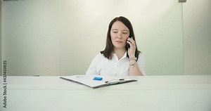 Animal vet clinic woman receptionist taking call and making notes looking at camera