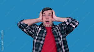 A surprised man screams while holding his head with both hands.
