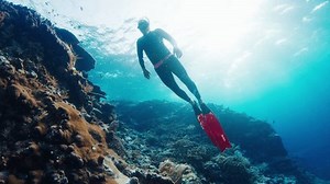 Freediver swims underwater in the sea and glides over the coral reef