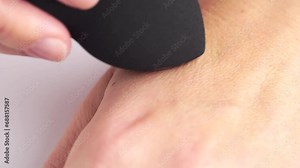 Woman makes foundation on the skin using beauty blender. Beauty blender on woman hand. Woman using a sponge for applying foundation tone. Professional tools for makeup, cosmetics products concept.