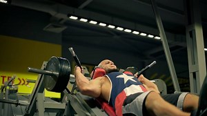 bald athletic man beard is focused on leg workouts in spacious gym. He is using leg press machine and demonstrating impressive effort