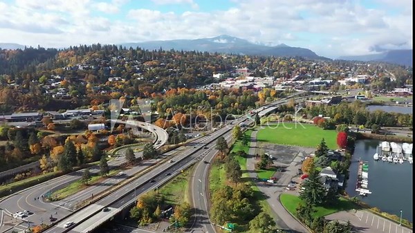 4K aerial drone footage of Hood River, Oregon showing cityscape, I-84 freeway, colorful trees in fall season, Columbia River marina, and distant mountains. Scenic travel video from Pacific Northwest