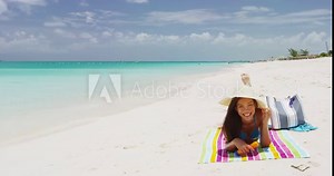 Sunscreen woman applying suntan lotion on nose lying in bikini. Beautiful smiling happy asian woman with suntan cream in bottle lying on beach during summer travel vacation. Multiracial female model Stock Video
