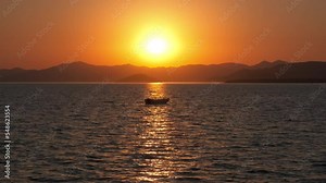 Silhouette of yacht on afterglow at sky. An alone yacht silhouette sailing in the calm sea water in nightfall. A concept of fishing relaxation during summer.