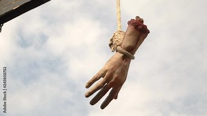An amputated, bloodied hand hangs on the gallows. Horror scene.
