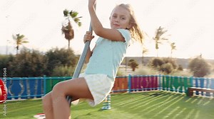 Happy smiling little girl move on zip line in playground or kindergarten yard. Zipline for children in adventure park. Ziplining activity in sunny summer day. Child having fun outdoors