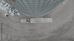Aerial top shot of semi loading corn at farmstead grain bin through trucks.