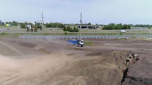 Use of heavy equipment in construction industry. Scene. Truck moves at a construction site covered with sand and gravel.