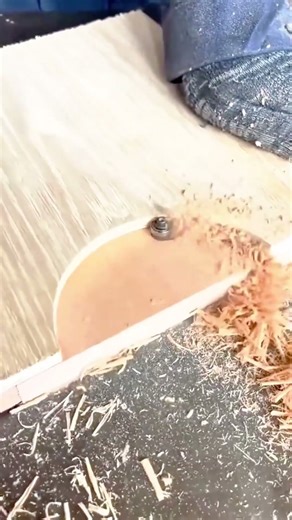 using a router tool to carefully trim and shape the edge of a wooden board during woodworking task