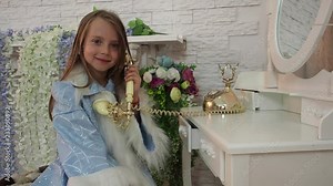 The little girl speaks by phone and smiles. The fairy tale Christmas character sits in the beautiful room at the telephone set.