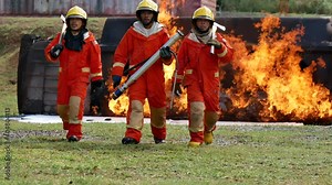 Firefighter fighting with fire flame protection property. Fireman wear hard hat, body safe suit uniform for protection from fire operation. Rescue trained in fire fighting extinguisher hazardous fires