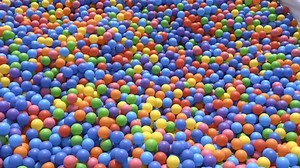 The girl is falling in the pool with colored balls.