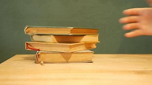 Stacked old books on a wooden surface with a plain background