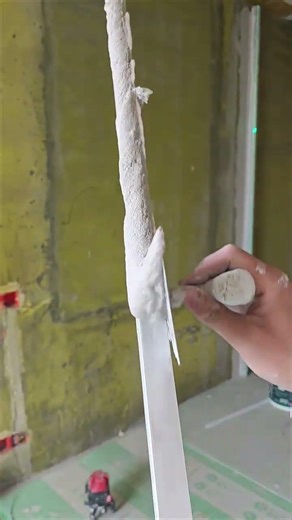 applying plaster on wall using laser guide and trowel