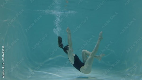 Elegant slim attractive sporty fit woman in swimsuit training synchronized swimming choreographed routine, practicing head to knee pose underwater in swimming pool during workout.