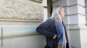 Young nervous woman standing on the street waiting her friend or boyfriend who is late to date. Hungry female wait for companion or colleague to go to the lunch to restaurant or cafeteria.