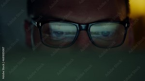 IT programmer, a man with glasses, works at night with a portable laptop. His face expresses seriousness as he carefully studies the information on the screen. Scores reflect the changing data picture