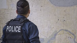Black police officer looking at a map in precinct close up