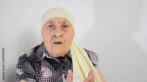 The wrinkled face of an old grandmother. Grandmother's face close up. Grandma sings. An aged mother. Seniors concept. Old grandmother on a light background. Women's Day. Social advertisement