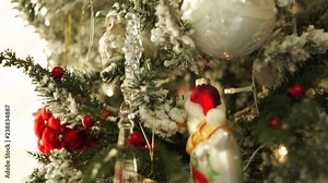 Christmas tree with artificial snow decorated with red and white christmas tree toys. Christmas tree balls, transparent glass toys, artificial berries and shinning lights on christmas tree, close-up.