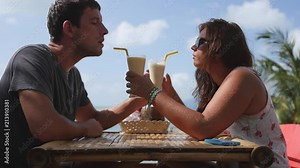 A man and a woman on a date in a cafe are drinking delicious cocktails from each other through tubes. Slow motion, HD, 1920x1080