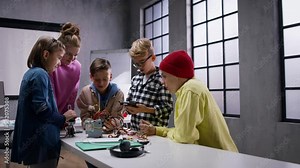 Kids with teacher working together on project with electric toys and robots at robotics classroom