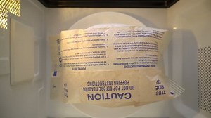 Top view making popcorn in a paper bag in the microwave. Popped popcorn bag rotating in microwave oven.