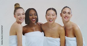 Slow motion of beautiful young smiling women of different ethnicities with perfect firm and slim body in white bathing towels dancing and having fun isolated on white background.