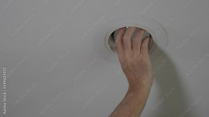 Electrician installing new light bulb in recessed ceiling light fixture. Man replacing burned out incandescent light bulb.