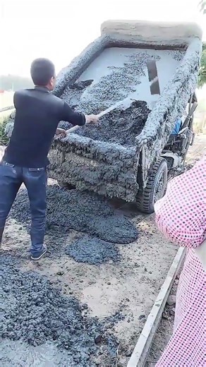 Pouring wet concrete from a truck using a rake for ground leveling and construction preparation work