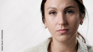 Woman is crying, tears. Woman with tears on her face on white background looks at camera. Close-up and slow motion