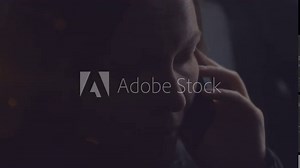 Woman talking on mobile phone from inside of the car at night, female person during telephone conversation. Shot through the window.