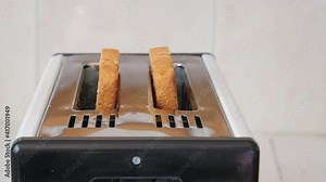 A toaster makes toast bread for breakfast close-up. Fried toast bread popping out of a toaster close-up. Fresh breakfast. 4K