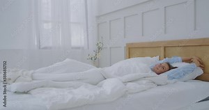 Beautiful Brunette Slowly Waking up in the Morning, Stretches and Gets Up from the Bed, Sun Shines on Her From the Big Window. Happy Young Girl Greets New Day