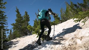 Hikers climbing up steep snow and ice terrain through trees during the day with crampons