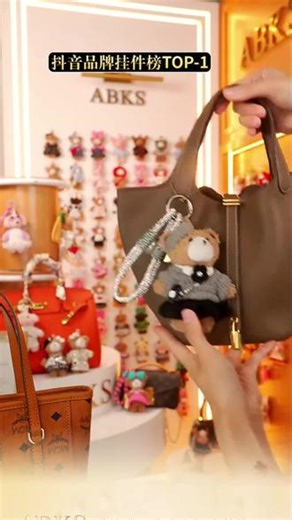 ABKS品牌高端包包挂件 宝子们，看这只小熊挂件！毛绒绒的，满是优雅的轻熟氛围。灰黑针织套装精致又利落，贝雷帽、花朵装饰与迷你挎包的细节衬出高级感，银灰挂绳自带轻奢质感。把它挂在包包上，仿佛将通勤的精致柔美感系于包身，每次瞥见这毛茸茸的优雅模样，都能被那股复古轻奢感打动，超有格调。 #ABKS #包包挂件 #包包搭配 #挂件挂饰 #正品