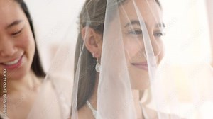 Woman helping bride with wedding veil in boutique for fashion, luxury fabric and choice design. Happy people or women in bridesmaid support fin dressing room for beauty or bridal customer service