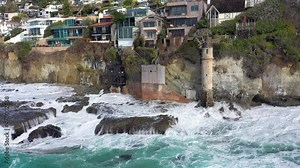 Aerial view of Victoria Beach with the famous pirate's Tower, an area of Orange County California for the wealthy and affluent, shows the crashing waves and they roll over jagged shoreline reefs.